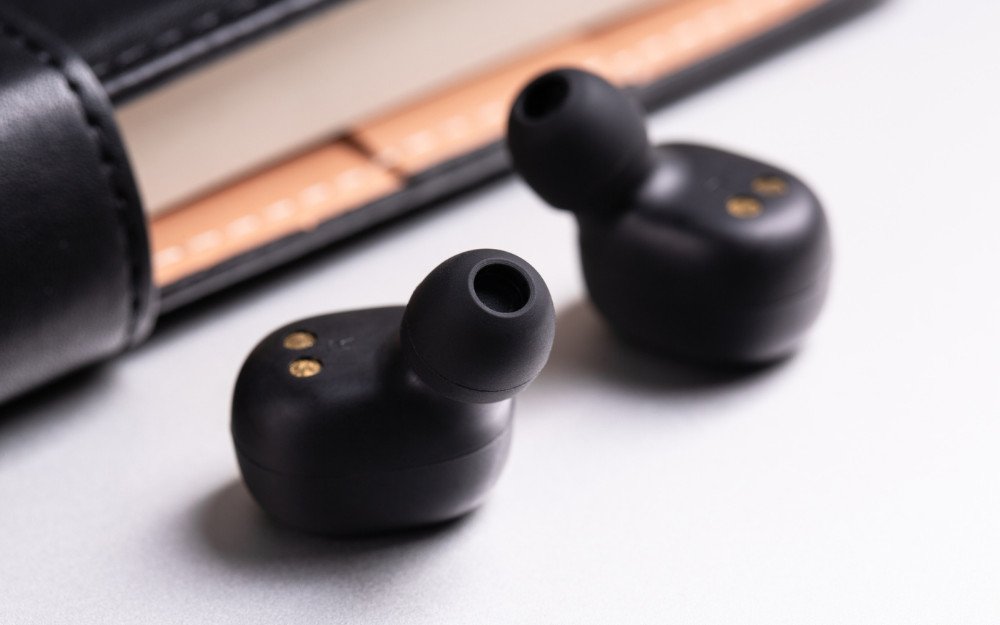 Một chiếc tai nghe bluetooth giá rẻ được đặt trên bàn làm việc, tượng trưng cho sự lựa chọn phù hợp cho học sinh, sinh viên và nhân viên văn phòng